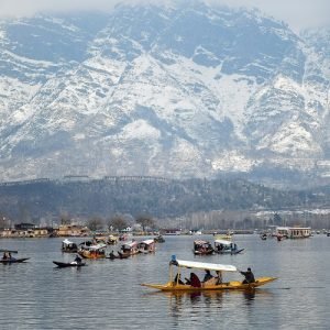 Srinagar, Feb 27 (ANI): Tourists enjoy a boat ride in Shikaras in the backdrop of snow-covered mountains on a sunny day, at Dal lake, in Srinagar on Sunday. (ANI Photo)